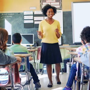 Smiling teacher in a classroom discussing history + social studies